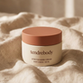 tendrebody Stretch Mark Cream jar with terracotta lid on warm linen